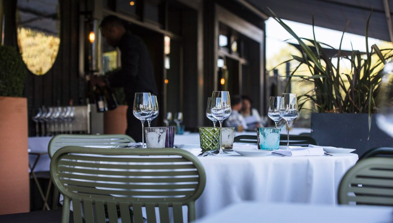 Intérieur élégant de restaurant avec une table bien dressée et des verres à vin, suggérant une expérience gastronomique haut de gamme.